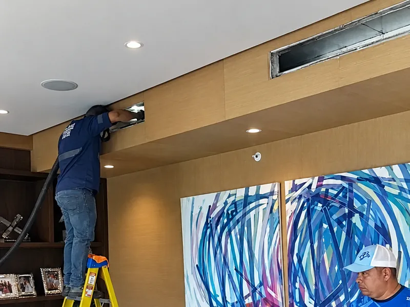 Un técnico en la escalera en el ducto y otro con la manguera del equipo de limpieza