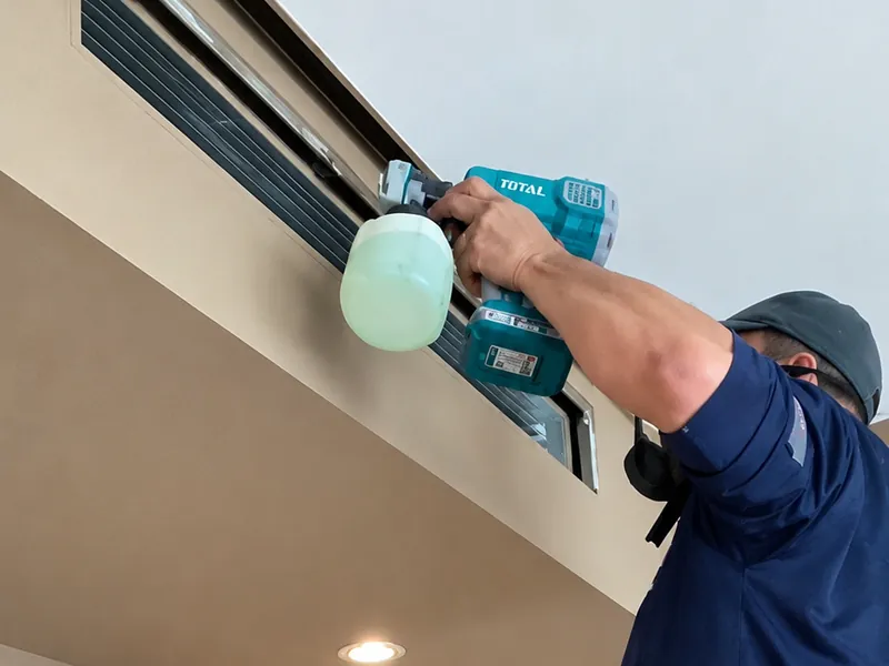 Técnico limpiando la rejilla de un ducto de aire acondicionado