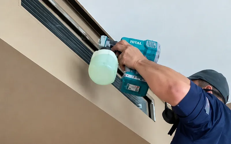 Técnico limpiando la rejilla de un ducto de aire acondicionado